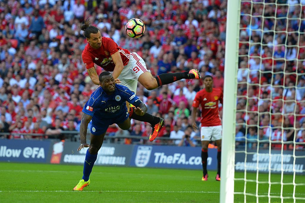 Manchester United's Swedish striker Zlatan Ibrahimovic (up) beats Leicester City's English defender Wes Morgan (down) to head in their second goal during the FA Community Shield football match between Manchester United and Leicester City at Wembley Stadium in London on August 7, 2016. / AFP / GLYN KIRK / NOT FOR MARKETING OR ADVERTISING USE / RESTRICTED TO EDITORIAL USE (Photo credit should read GLYN KIRK/AFP/Getty Images)