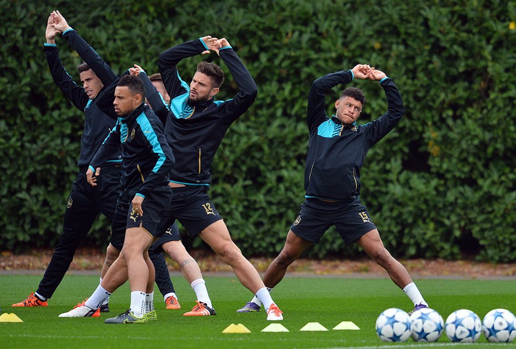 Arsenal's English striker Alex Oxlade-Chamberlain (R) stretches during a training session at their London Colney training ground in Hertfordshire, north of London, on October 19, 2015 on the eve of their UEFA Champions League group stage F football match against Bayern Munich.  AFP PHOTO / GLYN KIRK        (Photo credit should read GLYN KIRK/AFP/Getty Images)